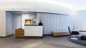 A modern reception area with a curved wall, a reception desk, a seating area, and a reception desk with framed artwork. - Modern 1 Bedroom in Downtown Boston (Boston)