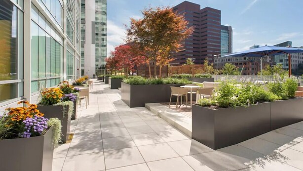 Un espace extérieur aménagé en terrasse, avec des sièges et des jardinières, entouré de bâtiments modernes.