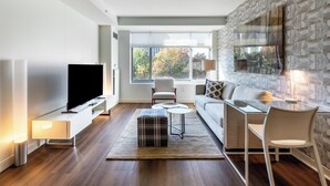 Un salon moderne avec un téléviseur à écran plat, un canapé, une table basse et une table à manger en verre.