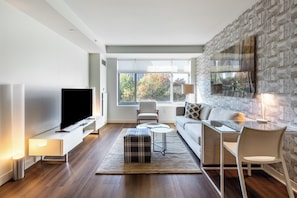 Un salon moderne avec un téléviseur à écran plat, un canapé, une table basse et une table à manger en verre.