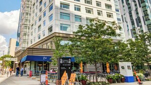 Un hôtel à plusieurs étages doté d’une façade moderne, avec un restaurant bien visible au rez-de-chaussée, et un ciel dégagé.