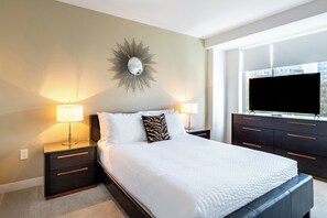 A hotel room with a large bed, two bedside tables with lamps, a wall-mounted mirror, a flat-screen TV, and a window with a city view. - Modern Two Bedroom with Views in Cambridge (Cambridge)