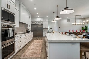 A modern kitchen with stainless steel appliances, white cabinetry, and pendant lighting.