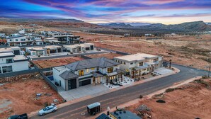 A residential area with modern houses, a main road, and a mountainous backdrop. - Pecan Valley 5205/5193|2 Private Pools&Spas, Private Pickleball Court, Game Room (Hurricane)