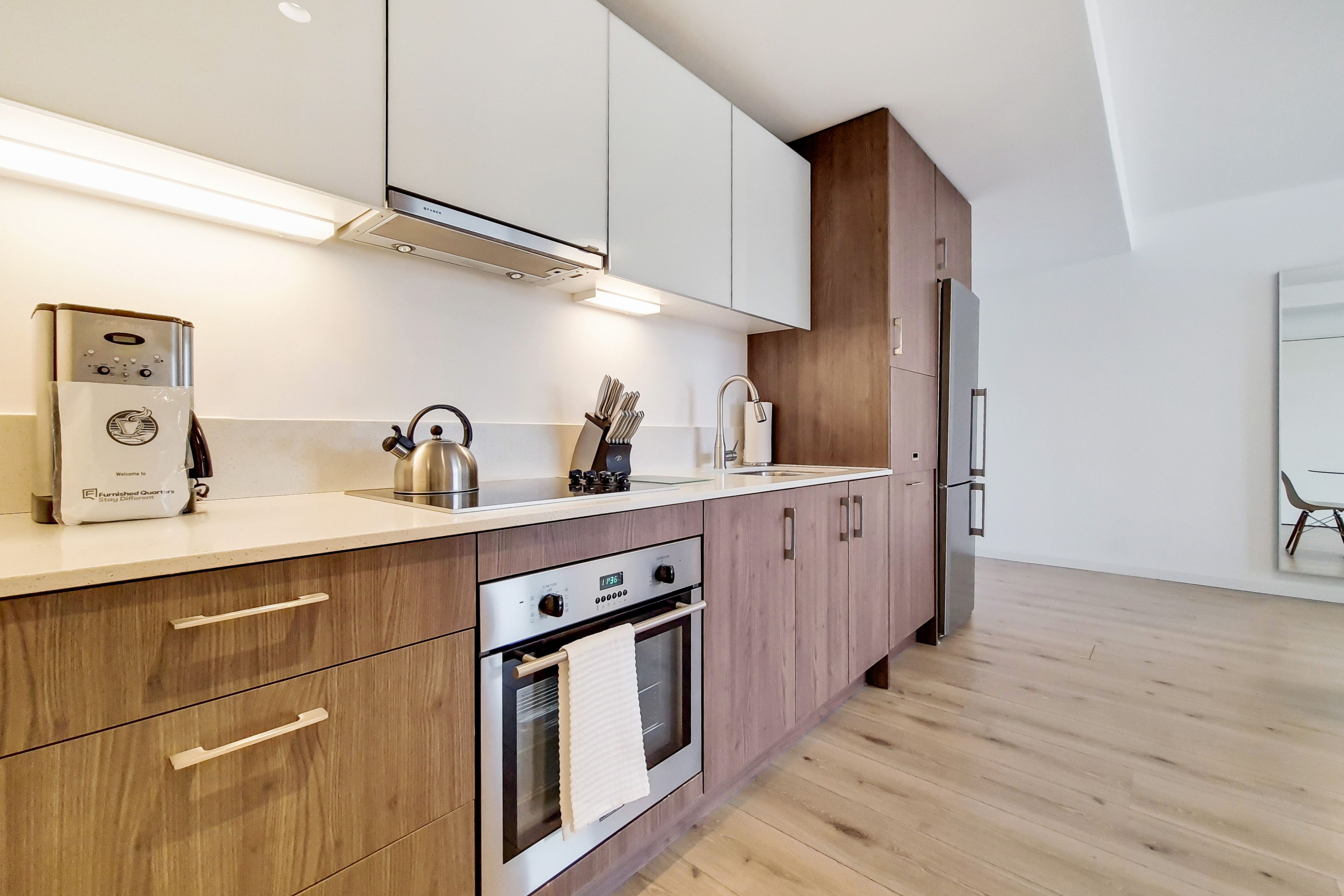 A modern kitchen with wooden cabinets, stainless steel appliances, and a built-in oven.