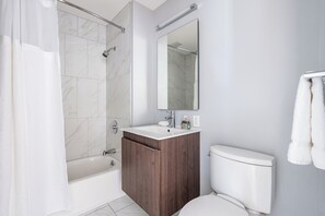 Un baño moderno con bañera, inodoro y tocador con espejo.