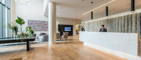 Et moderne receptionområde med en marmorindkasseringsdisk, siddeområde med sofaer og farverigt abstrakt vægkunst.
