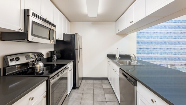 A modern kitchen with white cabinets, stainless steel appliances, and a black countertop.