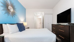A bedroom with a bed, a dresser, a TV, and a mirror.