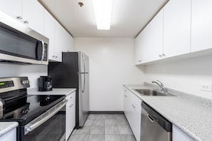 Una cucina moderna con mobili bianchi, un frigorifero in acciaio inossidabile, un piano cottura nero e una lavastoviglie.