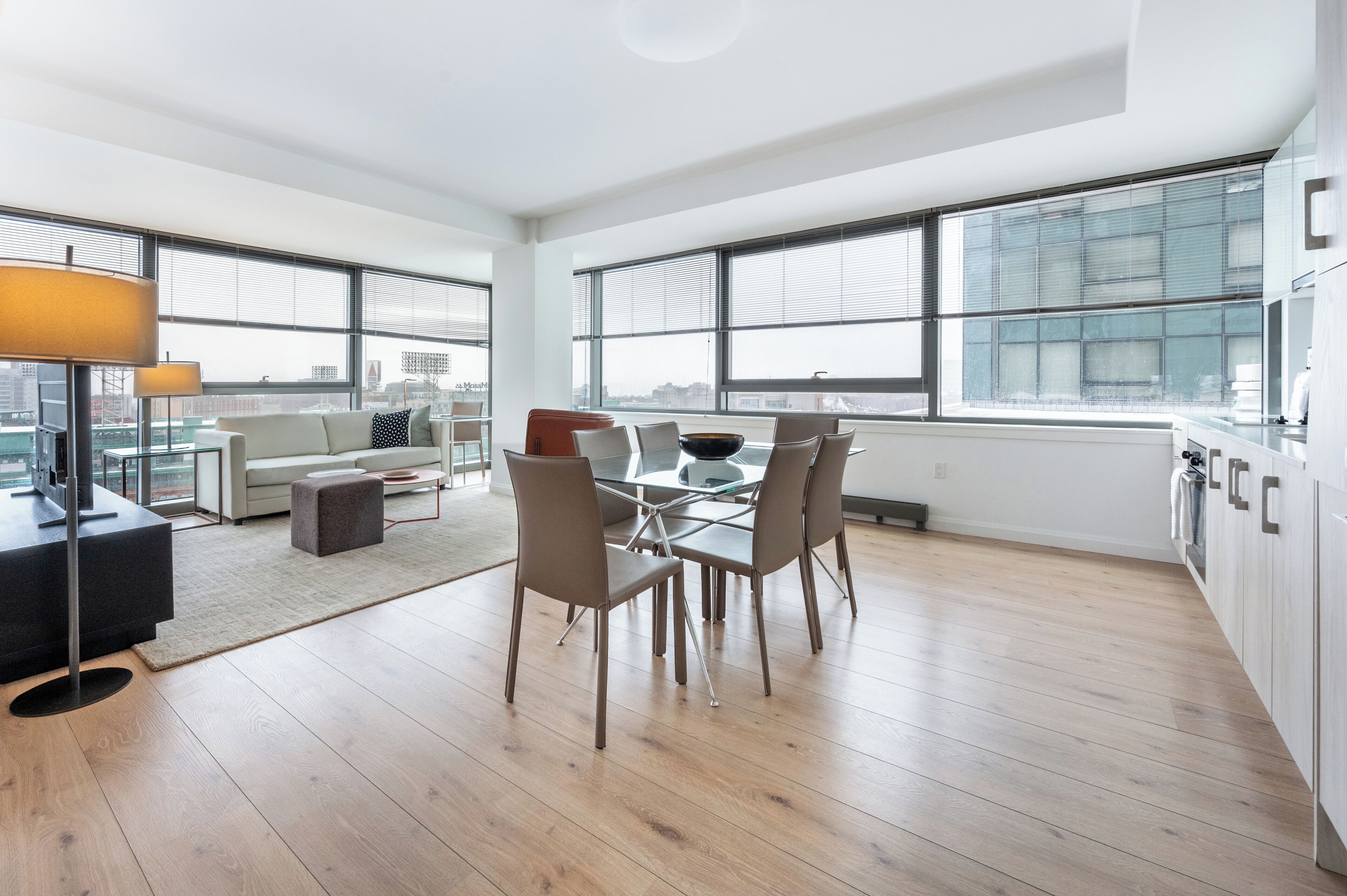 Un apartamento moderno con comedor, sofá, mesa de centro y ventanas amplias.