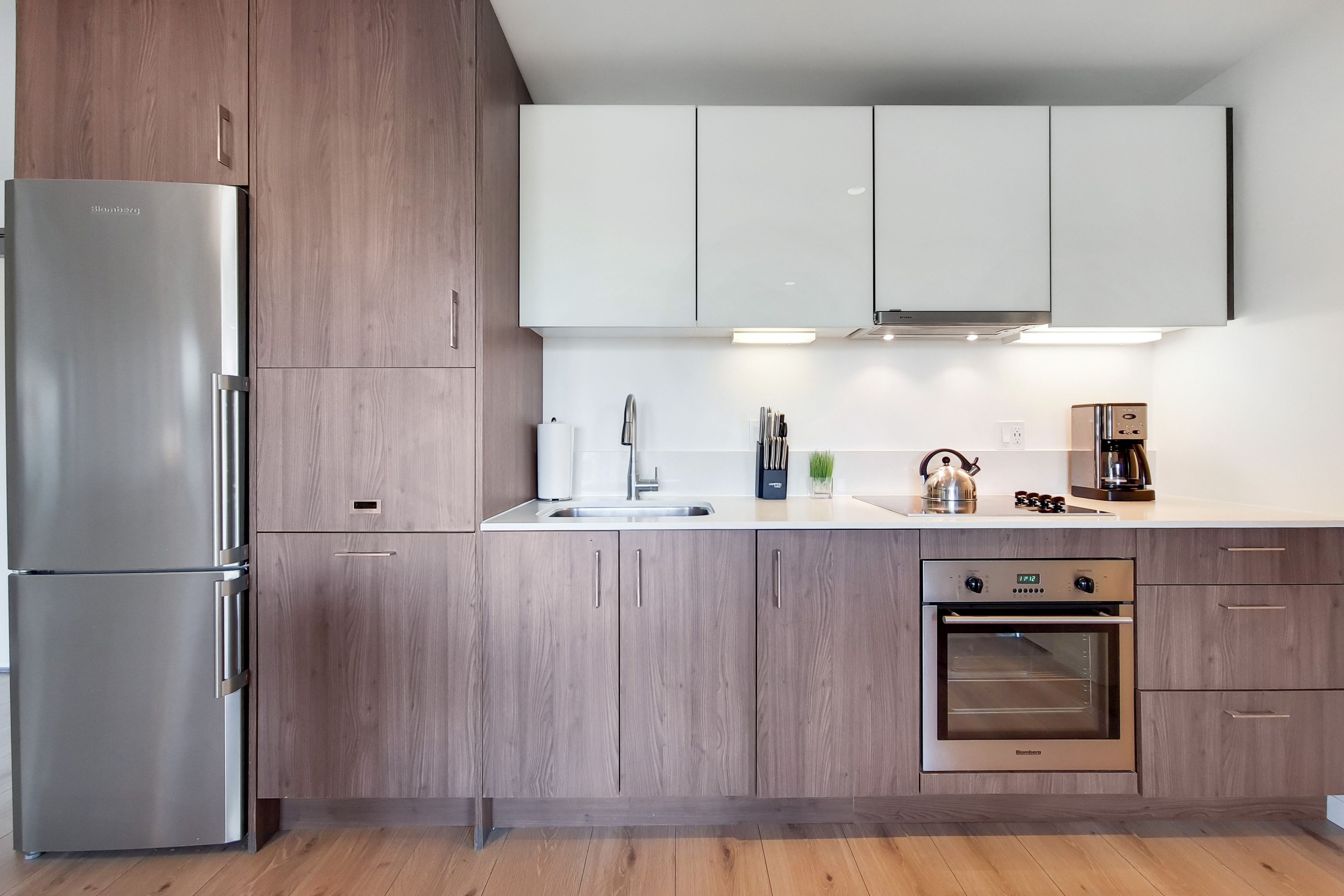A modern kitchen with stainless steel appliances, wooden cabinets, and a built-in oven.