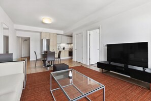 A modern apartment with a living room, dining area, kitchen, and a TV. - Spacious One Bedroom, Steps from Fenway Park (Boston)