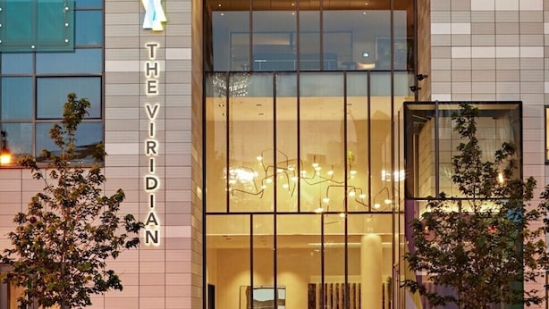 A hotel entrance with a modern design, featuring a large glass door and a sign that reads 'THE VIRIDIAN.' - Spacious One Bedroom, Steps from Fenway Park (Boston)