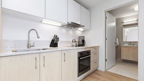 A modern kitchen with a stainless steel sink, a kettle, and a coffee maker. There are cabinets and a countertop. - Spacious One Bedroom, Steps from Fenway Park (Boston)