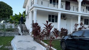 Een tweelaags huis met een balkon, een auto ervoor geparkeerd en een oprit naar de ingang.