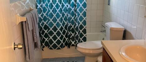 Un baño con cortina de ducha, inodoro, lavabo y una alfombra en el suelo.