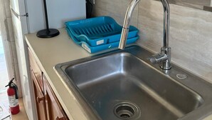 Een keuken met houten kastjes, een roestvrijstalen spoelbak en een blauwe afwasschaal.