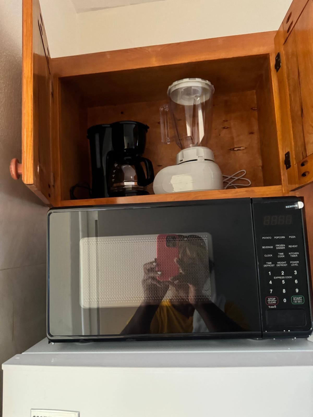 A microwave with a digital display and a control panel, placed on top of a white appliance.