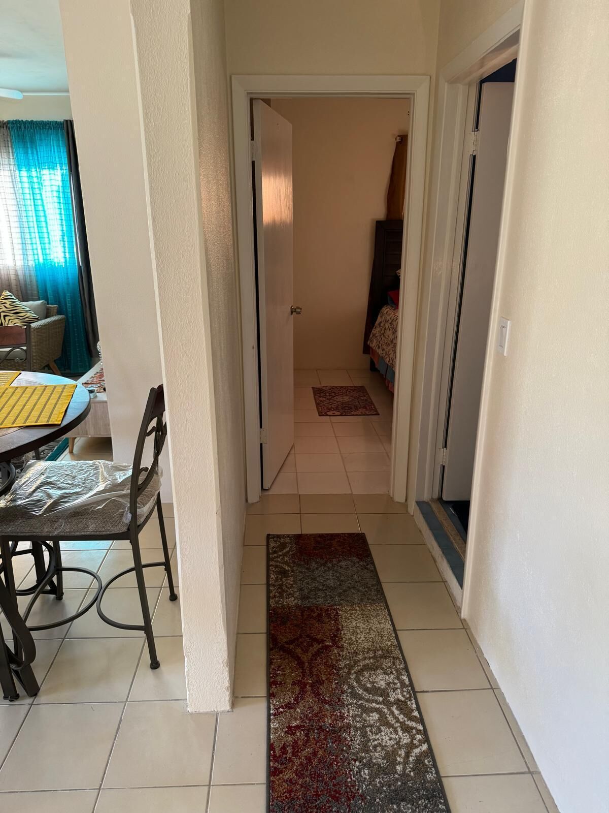 A narrow hallway with a dining area on one side and a bedroom on the other.