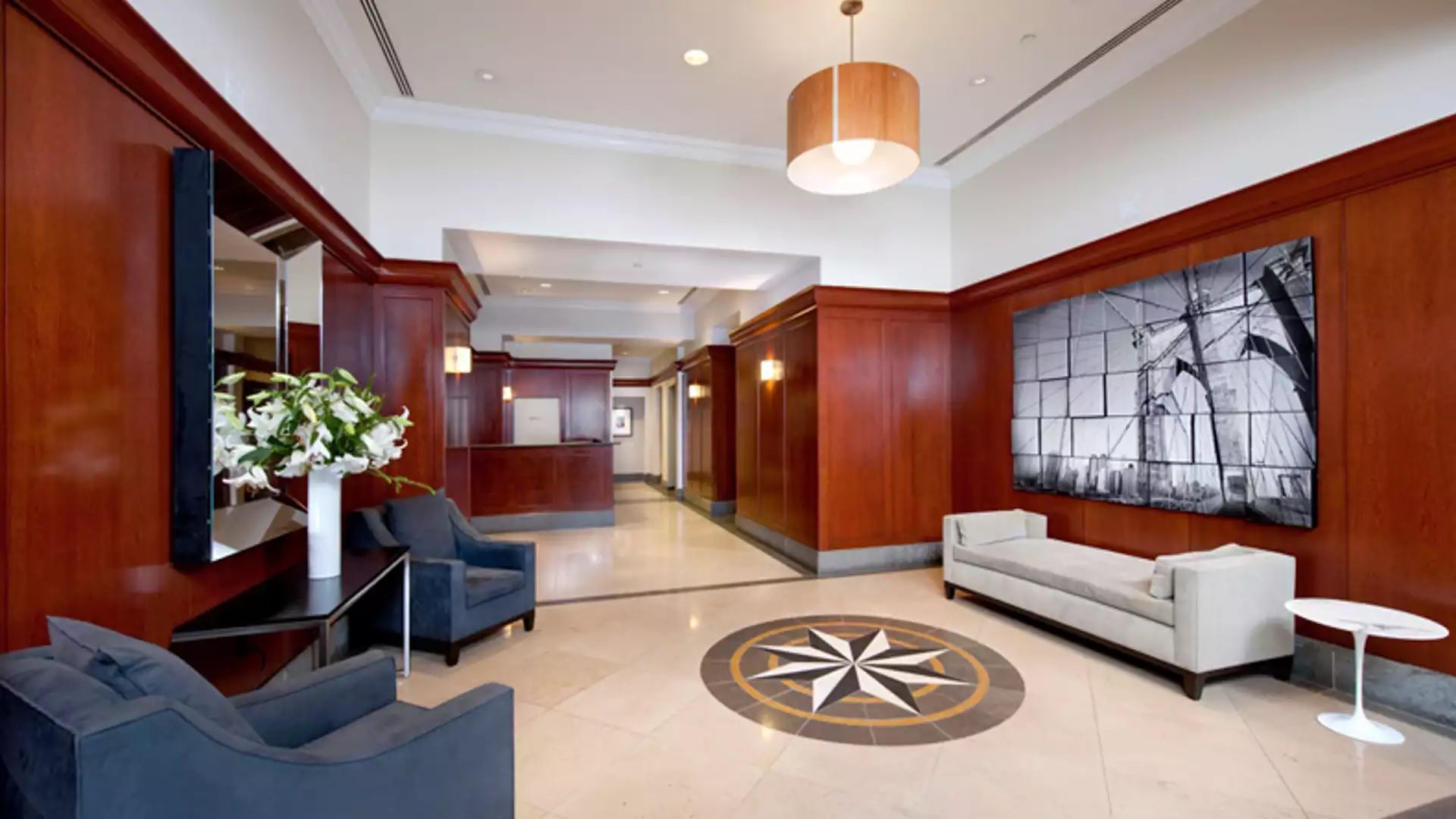 A hotel lobby with a reception desk, seating area, and a large abstract painting on the wall.