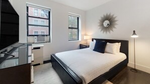 Ein modernes Schlafzimmer mit einem großen Bett, einem Schreibtisch und zwei Fenstern.