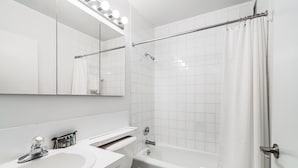 Une salle de bain moderne avec un lavabo, des toilettes et une baignoire, le tout de couleur blanche.