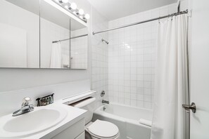 Een moderne badkamer met een wit wastafelmeubel, toilet en bad.