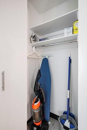 A small laundry area with a washing machine, an iron, and a mop.