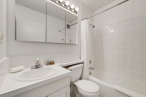 Un baño moderno con lavamanos, espejo y retrete blancos.