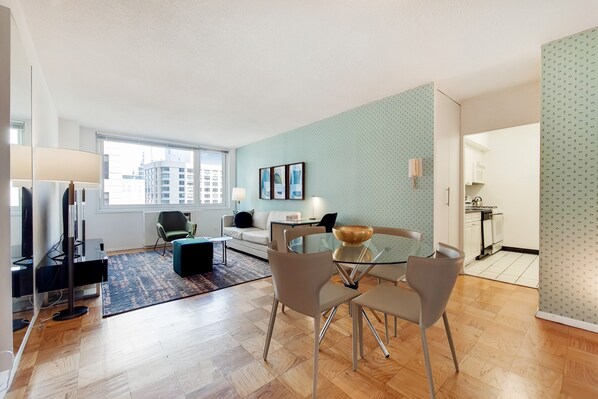 A modern living room with a glass dining table, a sofa, and a TV.