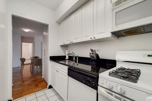 A modern kitchen with white cabinets, a black countertop, a dishwasher, and a stove.