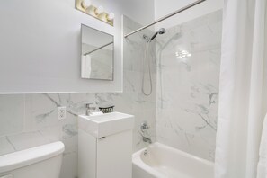 Ein modernes Badezimmer mit Waschbecken, Spiegel und Badewanne in Weiß.