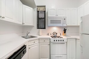 A compact kitchen with white cabinetry, a built-in microwave, a stove, and a dishwasher.