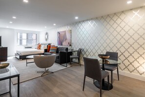A modern hotel room with a bed, a sofa, a dining table, and a TV. - Boutique Living | Greenwich | Doorman & W/D (New York)