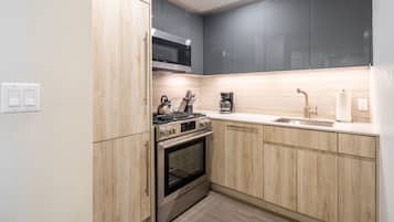 A modern kitchen with wooden cabinets, a stainless steel stove, and a microwave.