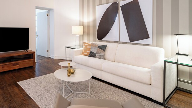 Ein modernes Wohnzimmer mit einer Couch, einem Couchtisch und einem Flachbildfernseher.