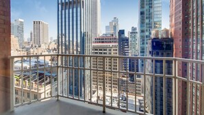 Un immeuble de grande hauteur offrant une vue sur le paysage urbain, vue à travers la rambarde d’un balcon.