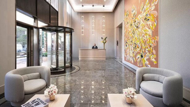 Un hall d’hôtel comprenant un comptoir d’accueil, un espace salon et une grande peinture abstraite.