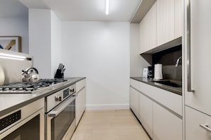 Une cuisine moderne dotée d’appareils électroménagers en acier inoxydable, d’un plan de travail noir et de meubles de couleur claire.
