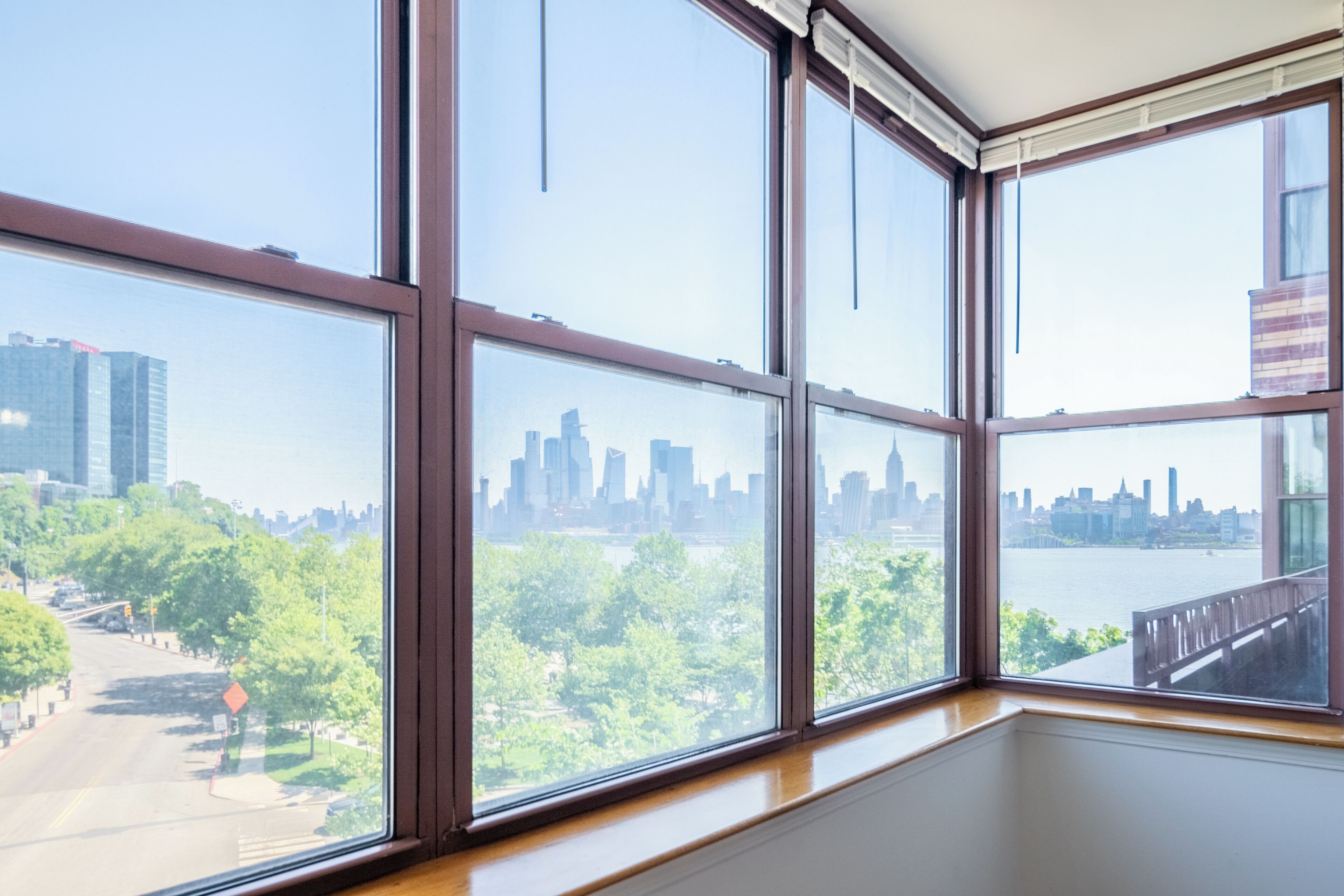 A room with large windows offering a view of a city skyline and a park.