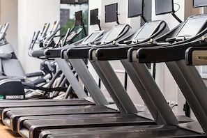 Eine Reihe von Laufbändern in einem Fitnessstudio, mit digitalen Anzeigen.