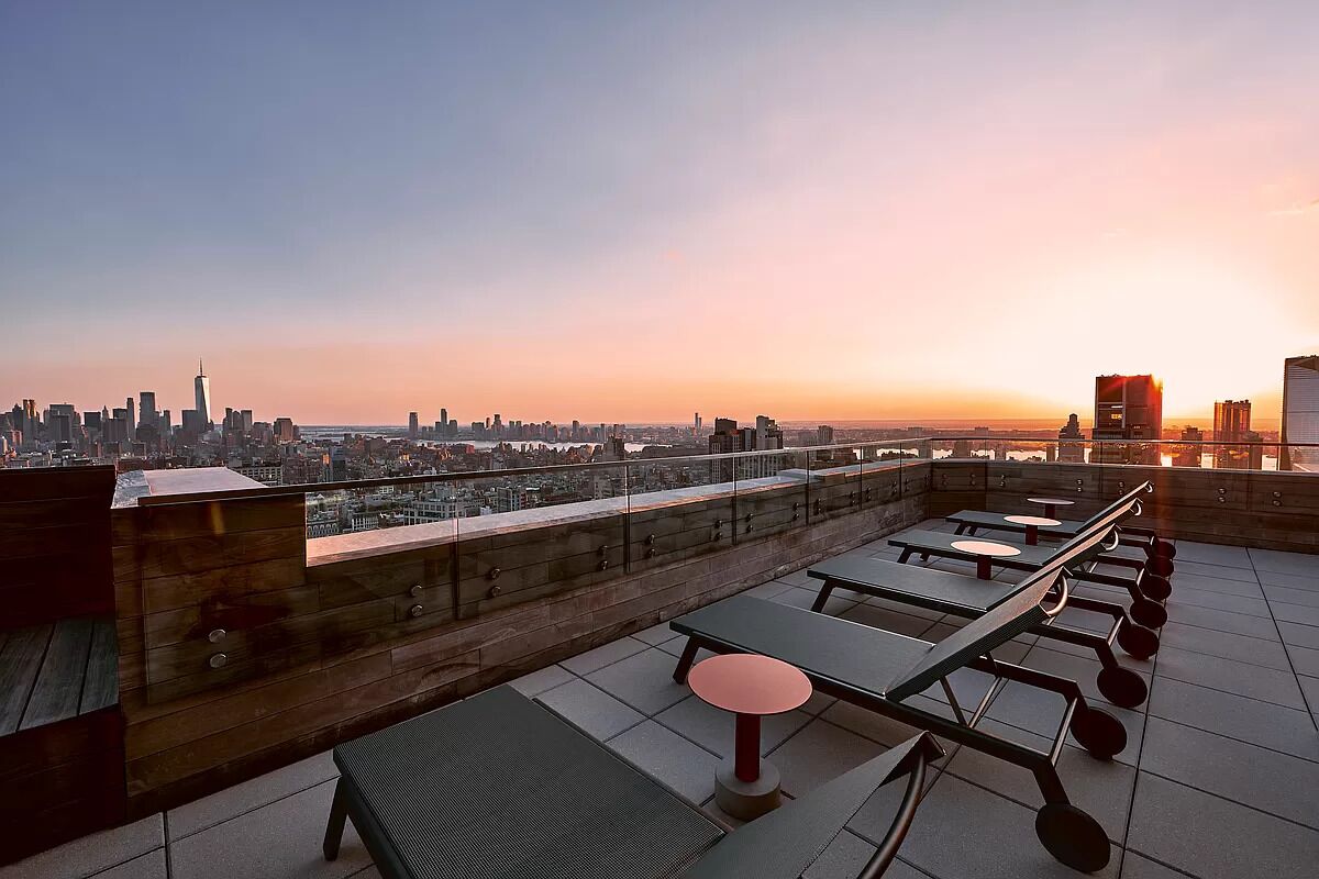 Una terraza en la azotea con mesas y sillas, con vistas al horizonte urbano.