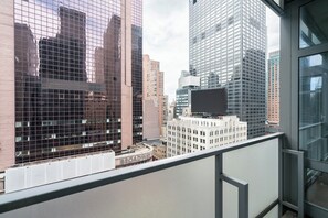 A cityscape with modern high-rise buildings, a historic building with a marquee, and a clear sky. - One Bedroom with Private Balcony in Times Square (New York)