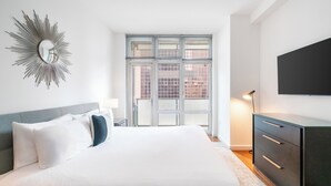 Un dormitorio con una cama grande, un espejo, un tocador y un televisor.