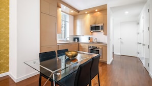Una cocina moderna con una mesa de comedor de vidrio, electrodomésticos de acero inoxidable y vistas al exterior.