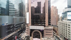 A multi-story building with a prominent arched entrance, surrounded by other high-rise buildings. - Live the Broadway Life | Times Square | W/D (New York)