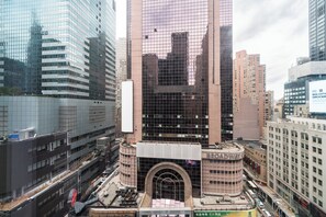 Un immeuble à plusieurs étages, dot é d’une entrée arquée imposante, et entouré d’autres immeubles de grande hauteur.
