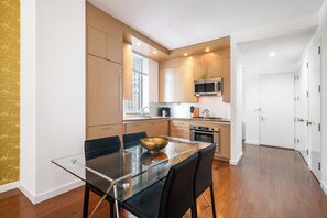 Una cocina moderna con una mesa de comedor de vidrio, electrodomésticos de acero inoxidable y vistas al exterior.