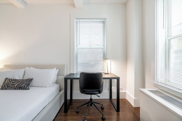A bedroom with a bed, a desk, and a chair.